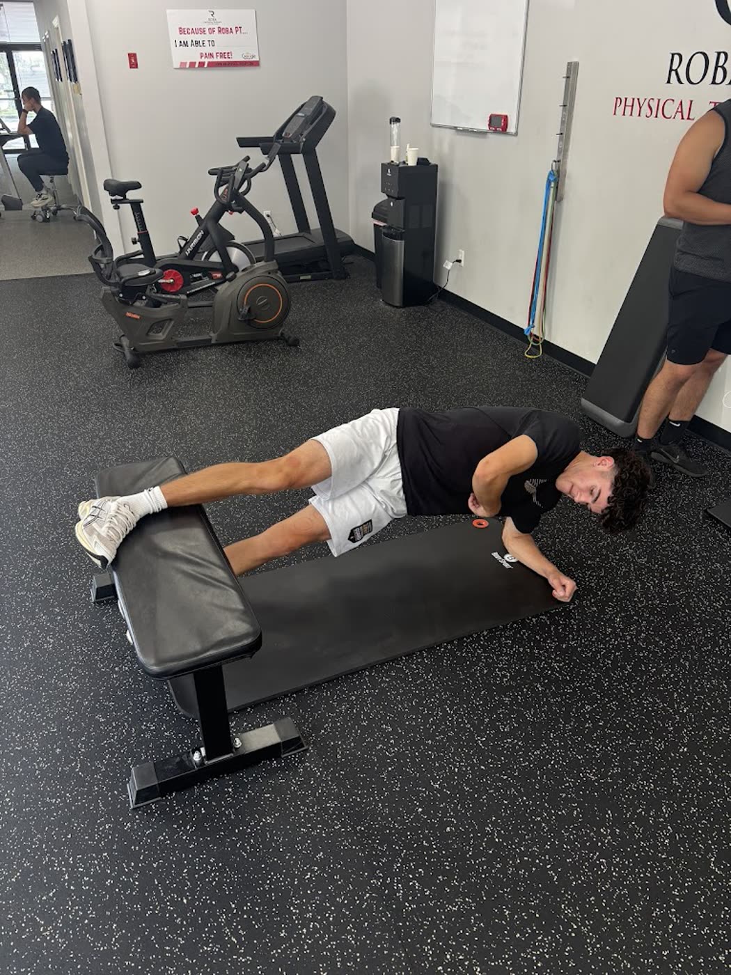 Patient doing a side plank on a bench in the clinic