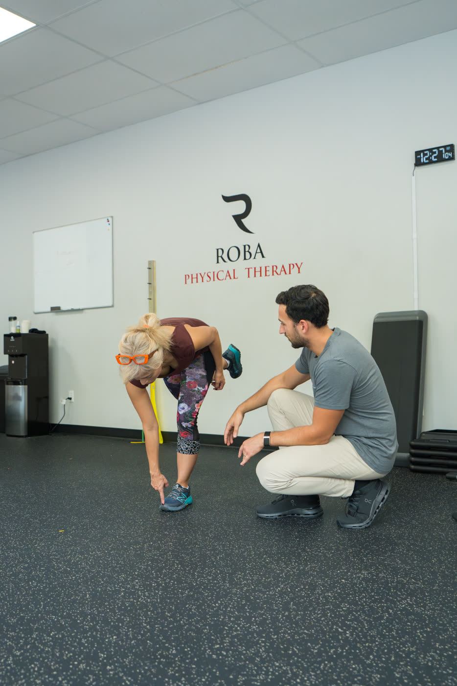 Therapist coaching a patient through an exercise in the clinic gym